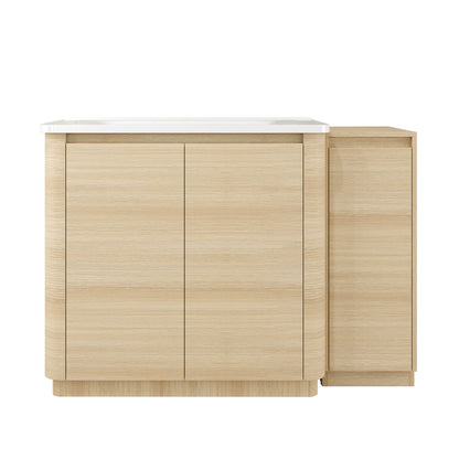 Freestanding bathroom vanity with white sink, light wood cabinet, and two closed doors