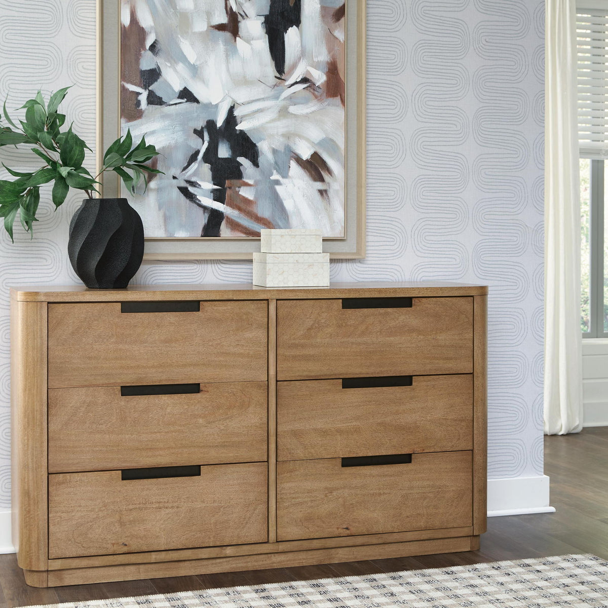 Light brown wood dresser with four drawers and black bar pulls