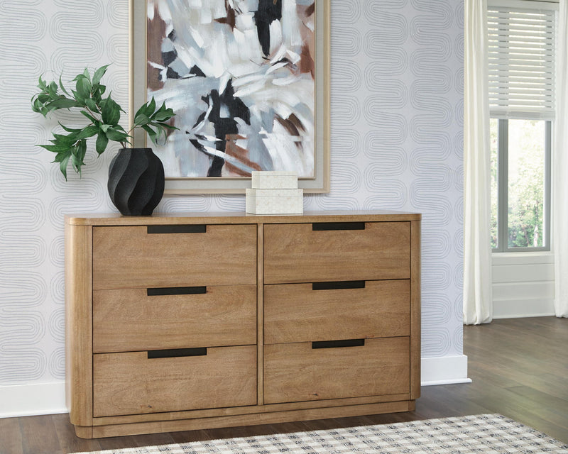 Light brown wood dresser with four drawers and black bar pulls