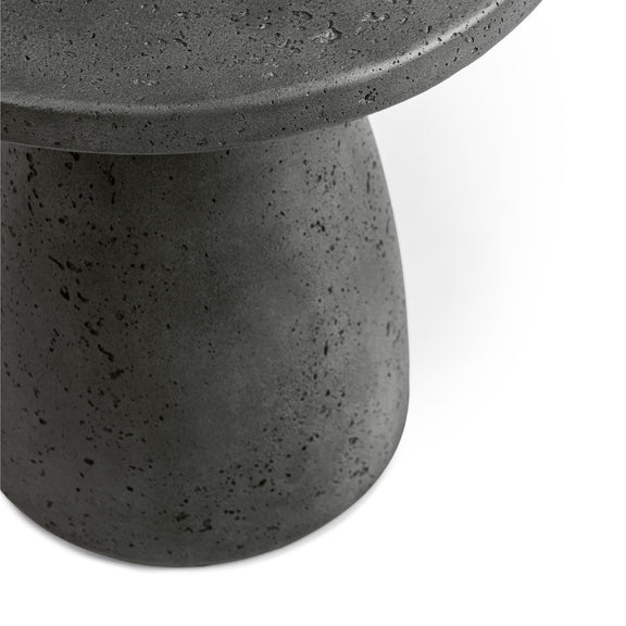 Outdoor accent table close-up: dark speckled tabletop edge and pedestal surface texture.