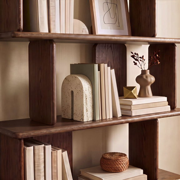 Beige travertine bookend on a shelf, arched front with vertical cutout