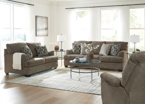 Taupe fabric living room sofa set with chair and ottoman, shown with pillows and throw blankets.