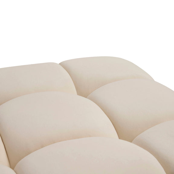 Close-up of beige modular ottoman top with rounded tufted cushions and panel seams