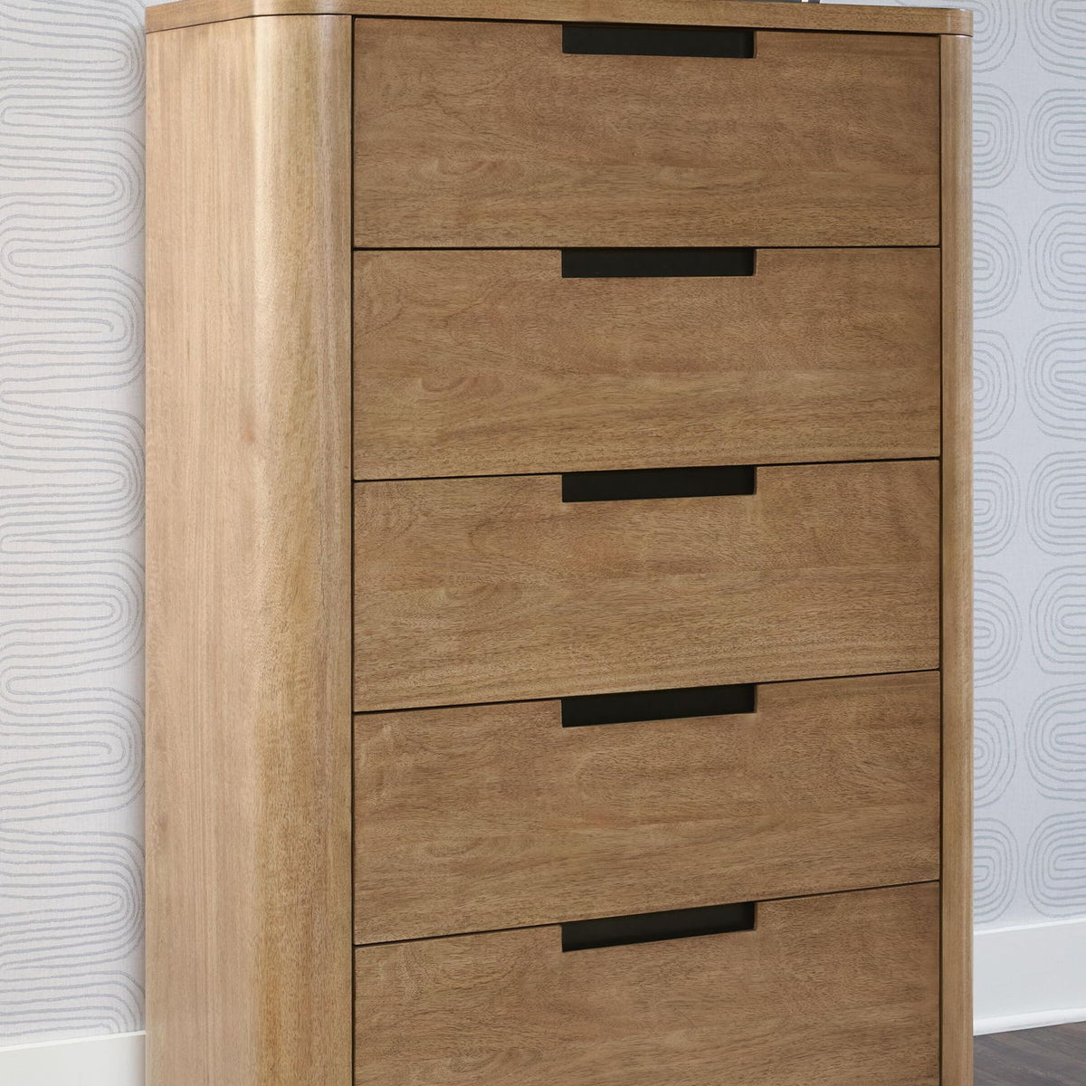 Light brown five-drawer chest, angled view, top shelf with stacked books
