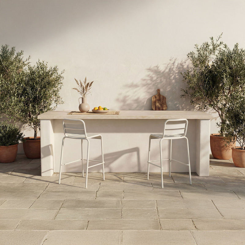 Two white outdoor bar stools with slatted backs, armless design on patio.