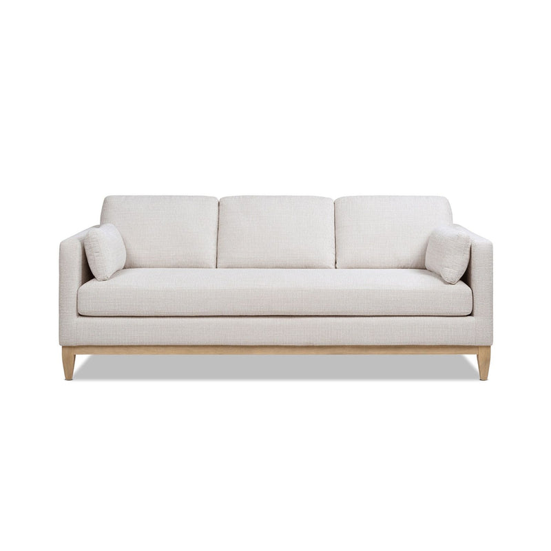Light beige fabric sofa with three back cushions, rounded arms, and tapered wood legs