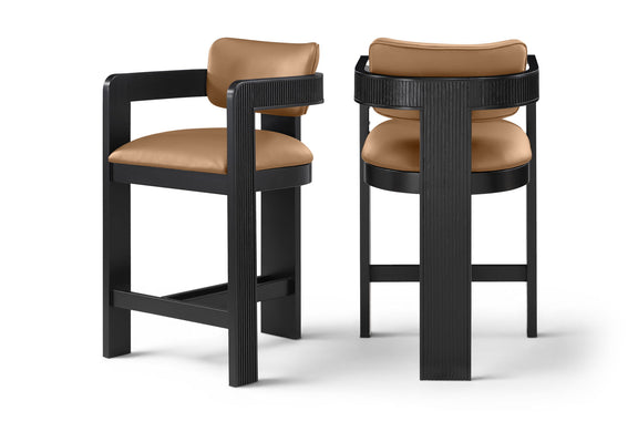 Two vegan leather counter stools with tan upholstered seats and black ribbed frames