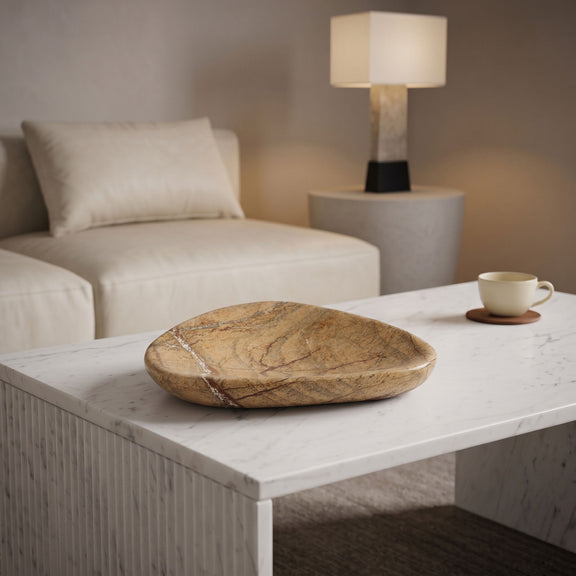 Beige marble bowl on white tabletop, shallow dish shape with natural stone pattern.