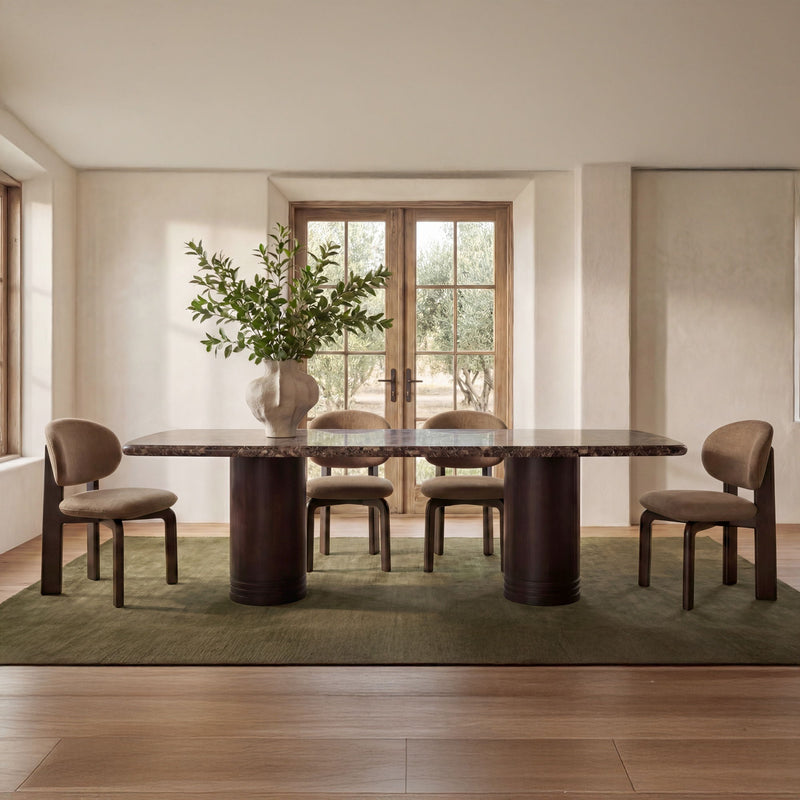 Dining table with dark marble top and brown pedestal base in a home dining room
