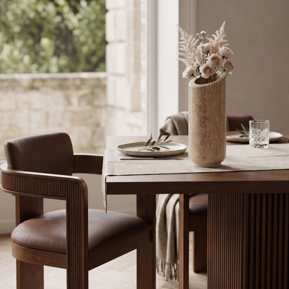 Beige travertine vase holding a small bouquet on a table