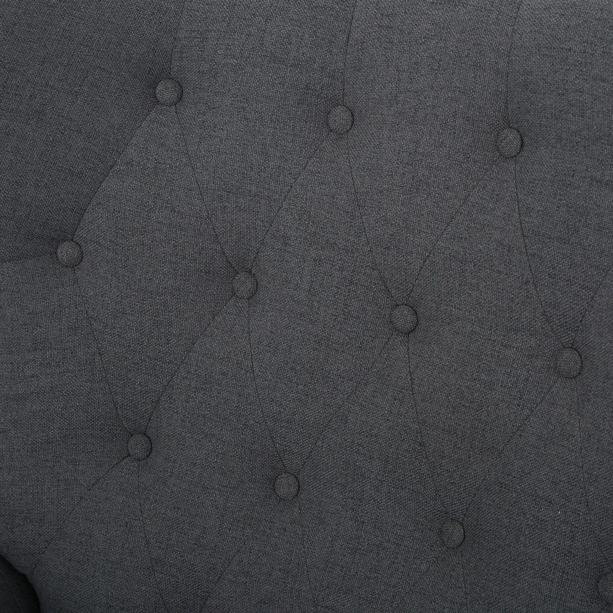 Dark gray tufted upholstery fabric close-up with button details.