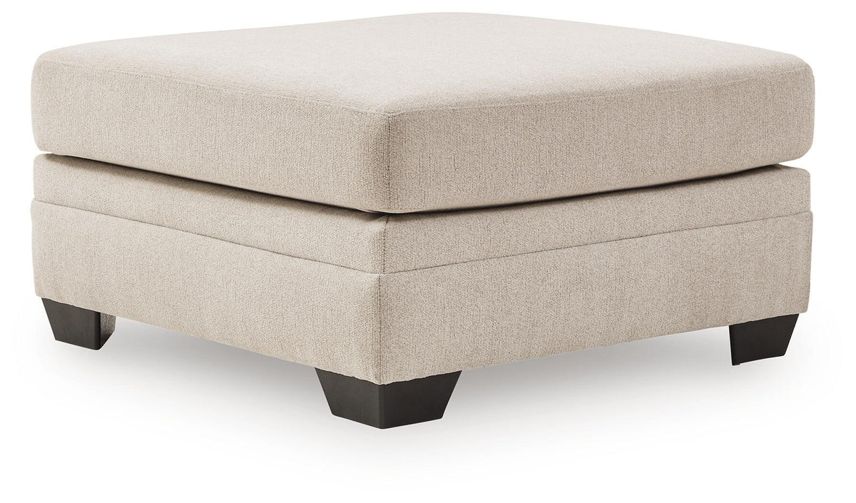Beige upholstered accent ottoman with square top, stacked panels, and dark legs