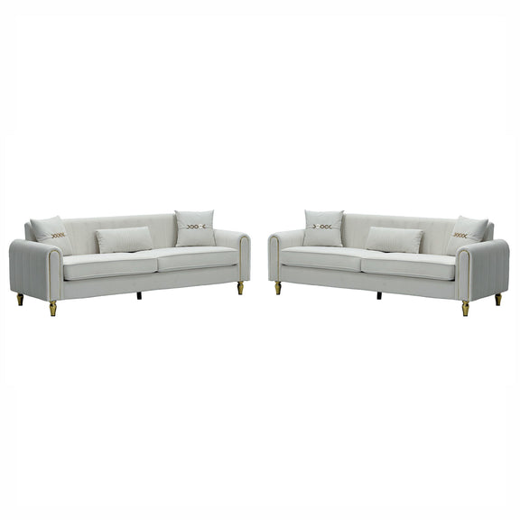 Two light-colored three-seat sofas with ribbed rounded arms and gold-tone legs