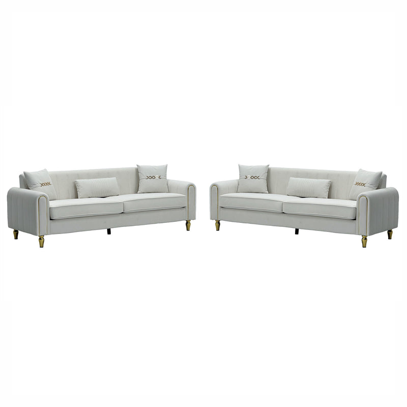Two light-colored three-seat sofas with ribbed rounded arms and gold-tone legs