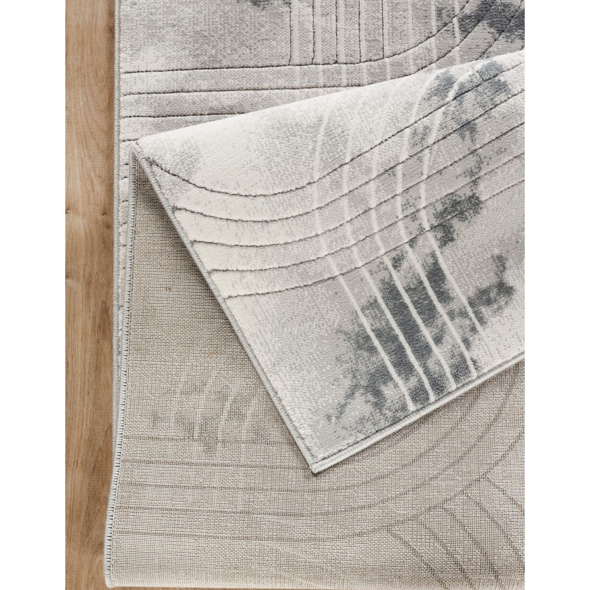 Gray area rug corner detail with textured geometric lines and blue-gray accents.