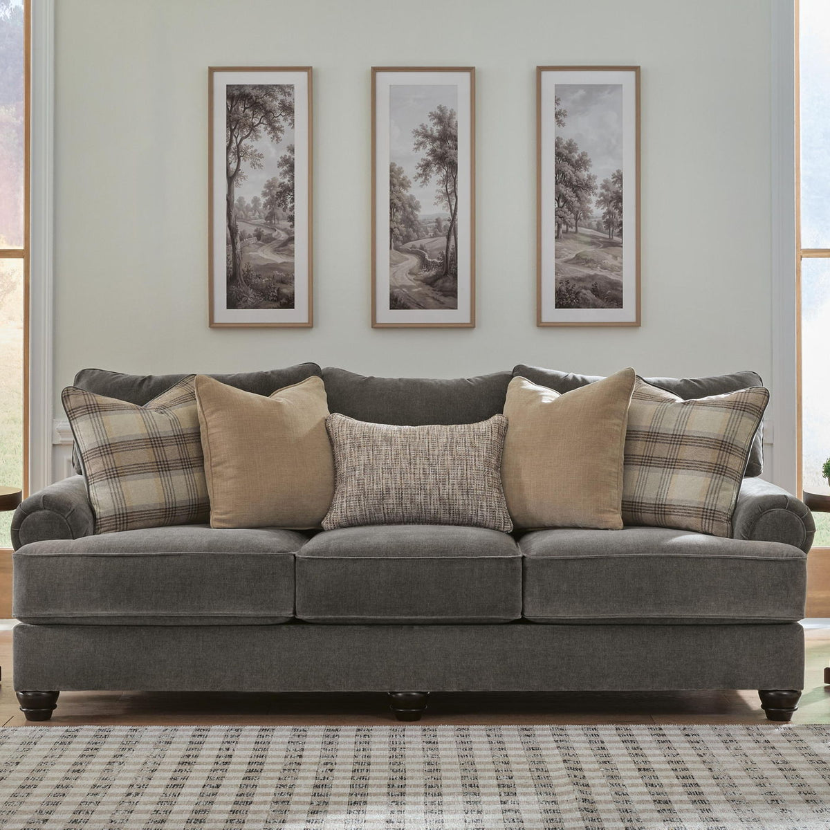 Dark gray upholstered sofa with rolled arms, tufted cushions, and patterned throw pillows