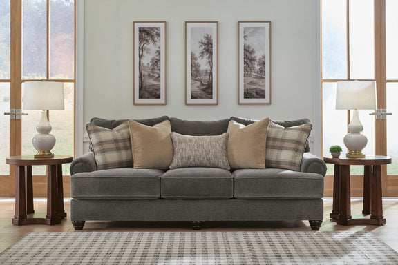 Dark gray upholstered sofa with rolled arms, tufted cushions, and patterned throw pillows