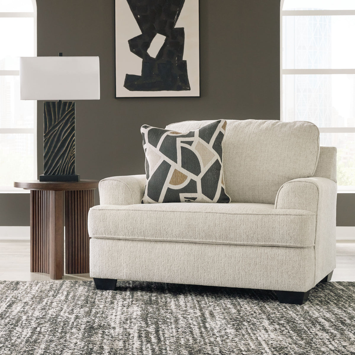 Light gray chair and a half with geometric throw pillow