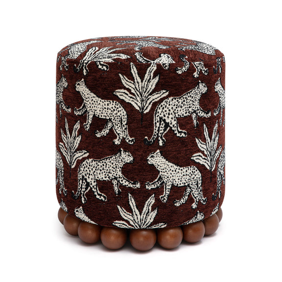 Dark brown fabric ottoman with white animal pattern and dark wood ball base.
