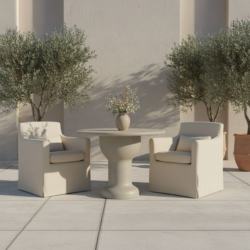 Cream outdoor slipcovered dining chair with seat cushion and armrests, outdoors.