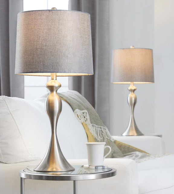Contemporary table lamp set with tan fabric shades and silver-toned bases on a sofa