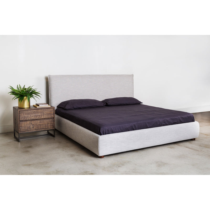 Light gray king bed with dark comforter and two pillows, upholstered headboard
