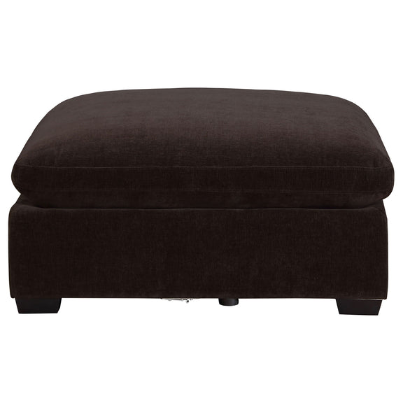 Black upholstered ottoman with thick cushion top and short wooden legs.