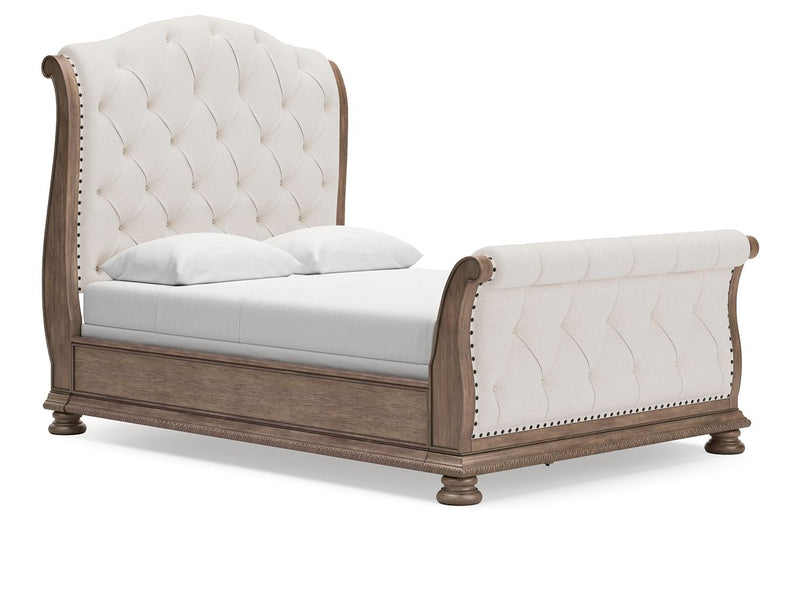 Light brown framed sleigh bed with tufted cream upholstery and nailhead trim