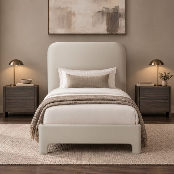 Beige upholstered bed with rounded headboard, white bedding and pillows, throw blanket