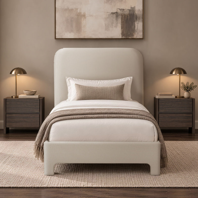 Beige upholstered bed with rounded headboard, white bedding and pillows, throw blanket