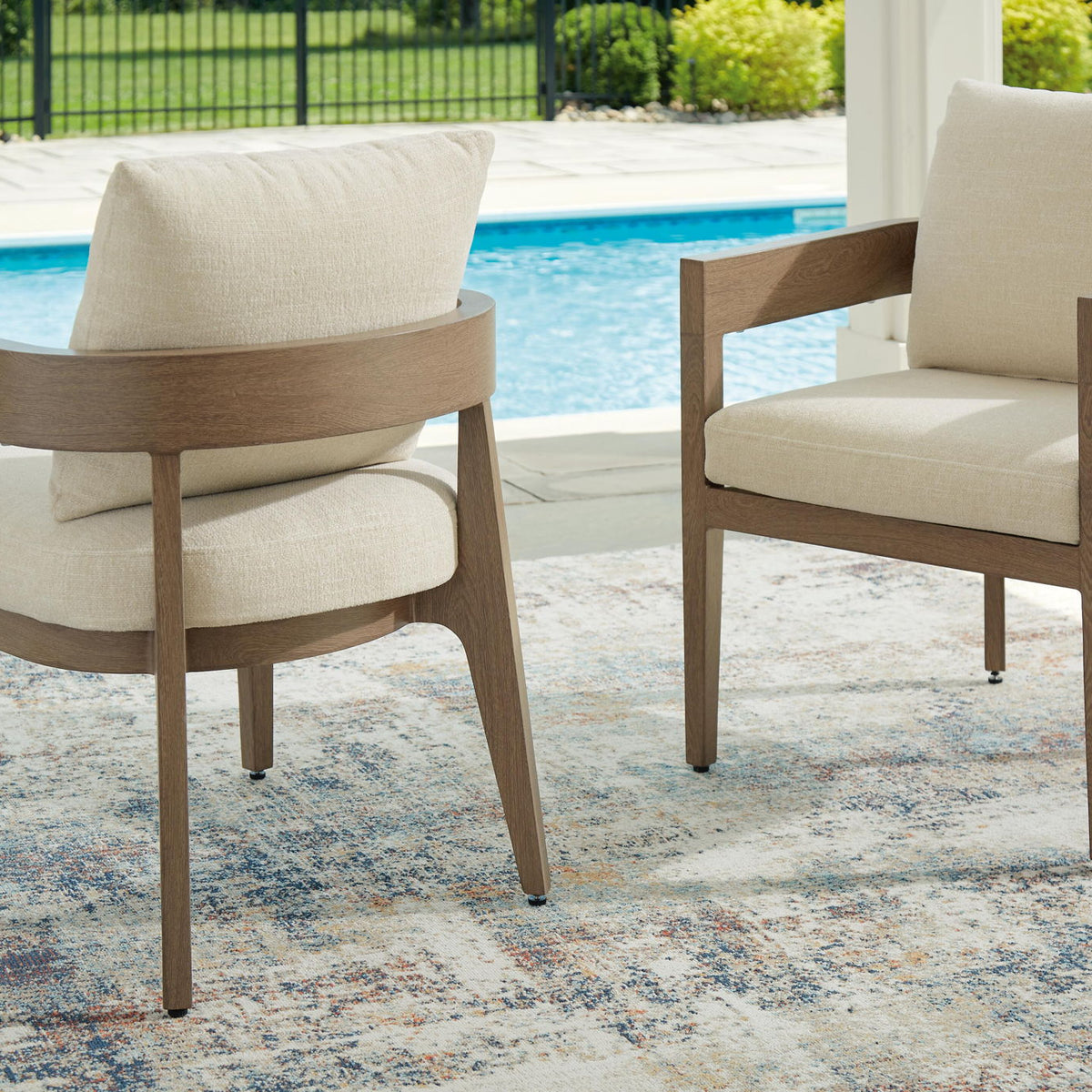 Two dark brown arm chairs with beige cushions
