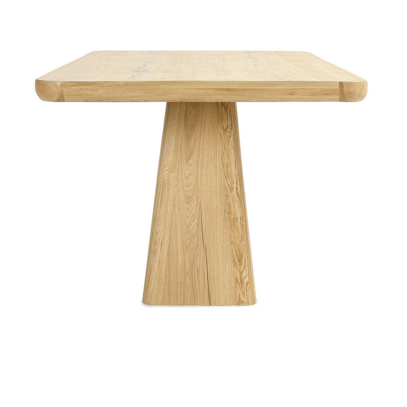Natural wood dining table with slightly rounded rectangular top and central pedestal