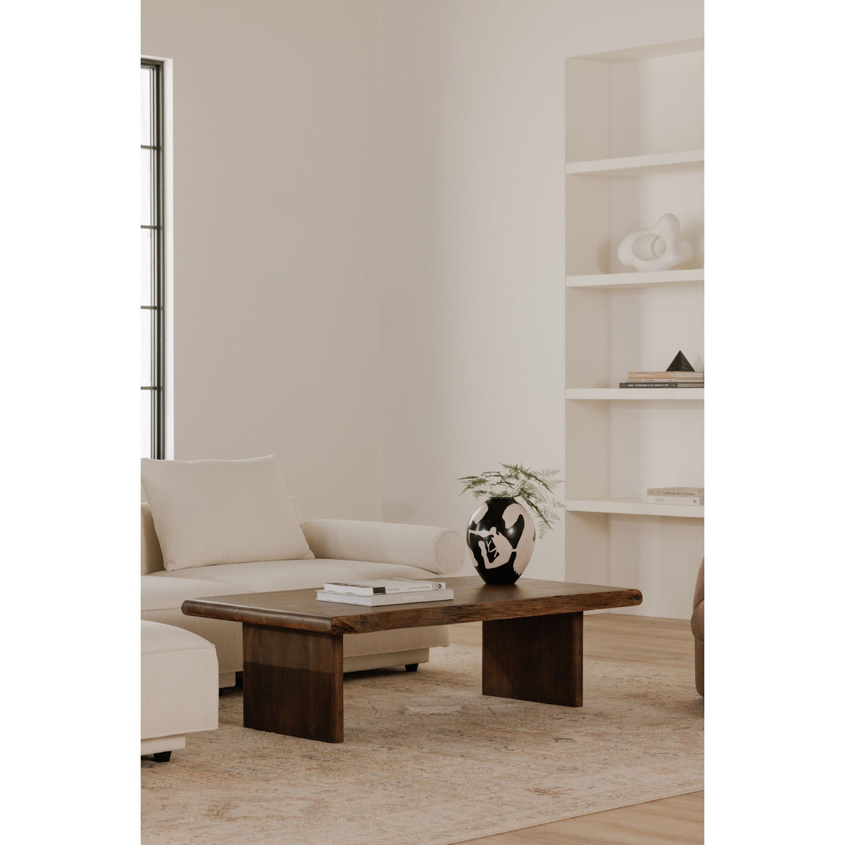 Brown wooden coffee table in front of white sofa, showing side profile