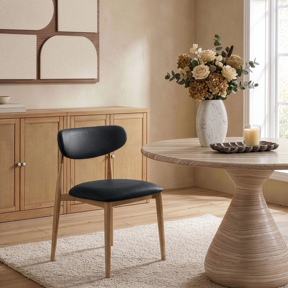 Vegan leather dining side chair with black cushioned seat and light wood legs
