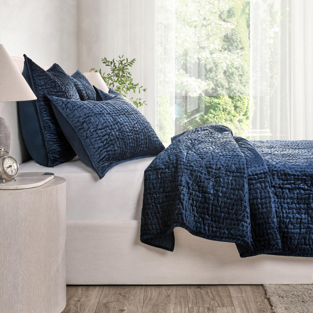 Navy velvet quilt with matching pillows on a bed