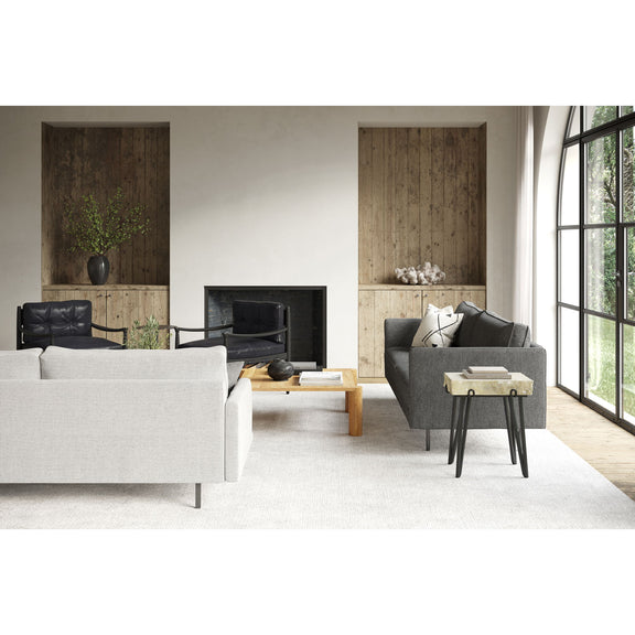 Sand stone accent table with black legs near armchairs and sofa