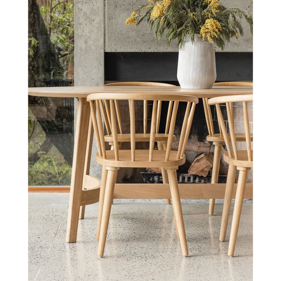Small dining table in natural light oak with slatted apron support under rounded top.