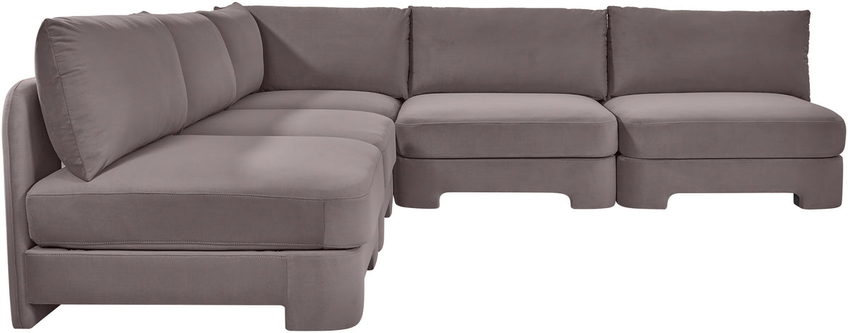 Light gray armless velvet sectional sofa with rounded seat corners and back pillows.