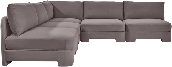 Light gray armless velvet sectional sofa with rounded seat corners and back pillows.