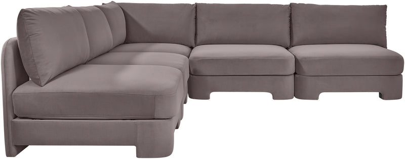 Light gray armless velvet sectional sofa with rounded seat corners and back pillows.