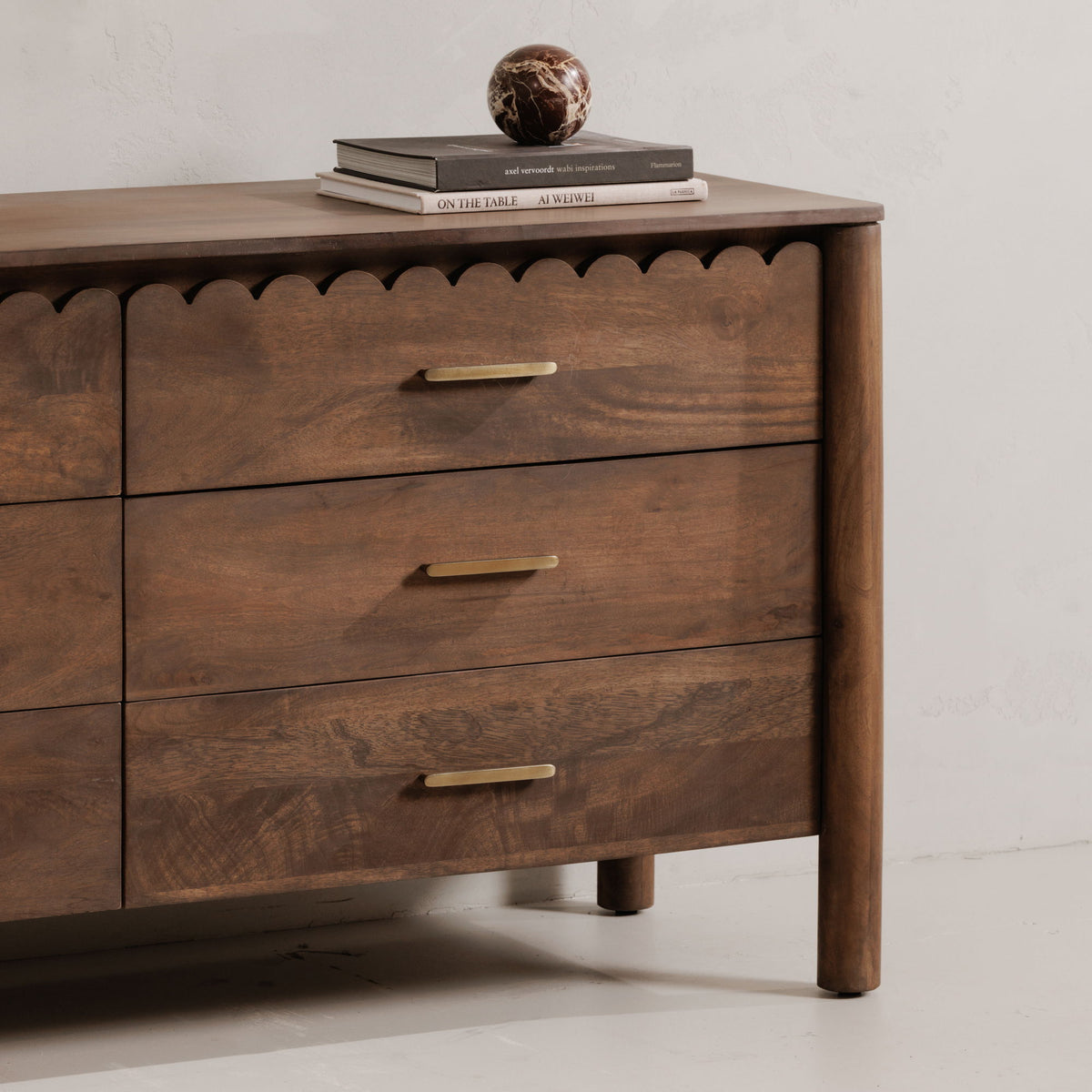 Brown dresser corner view with three drawers, gold bar pulls, and tapered legs