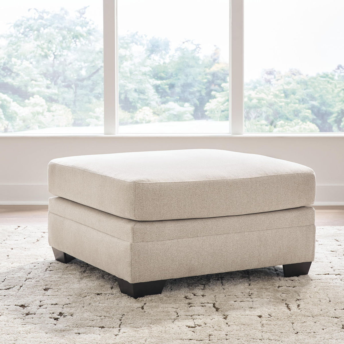 Light beige oversized ottoman with wide seat and dark block legs
