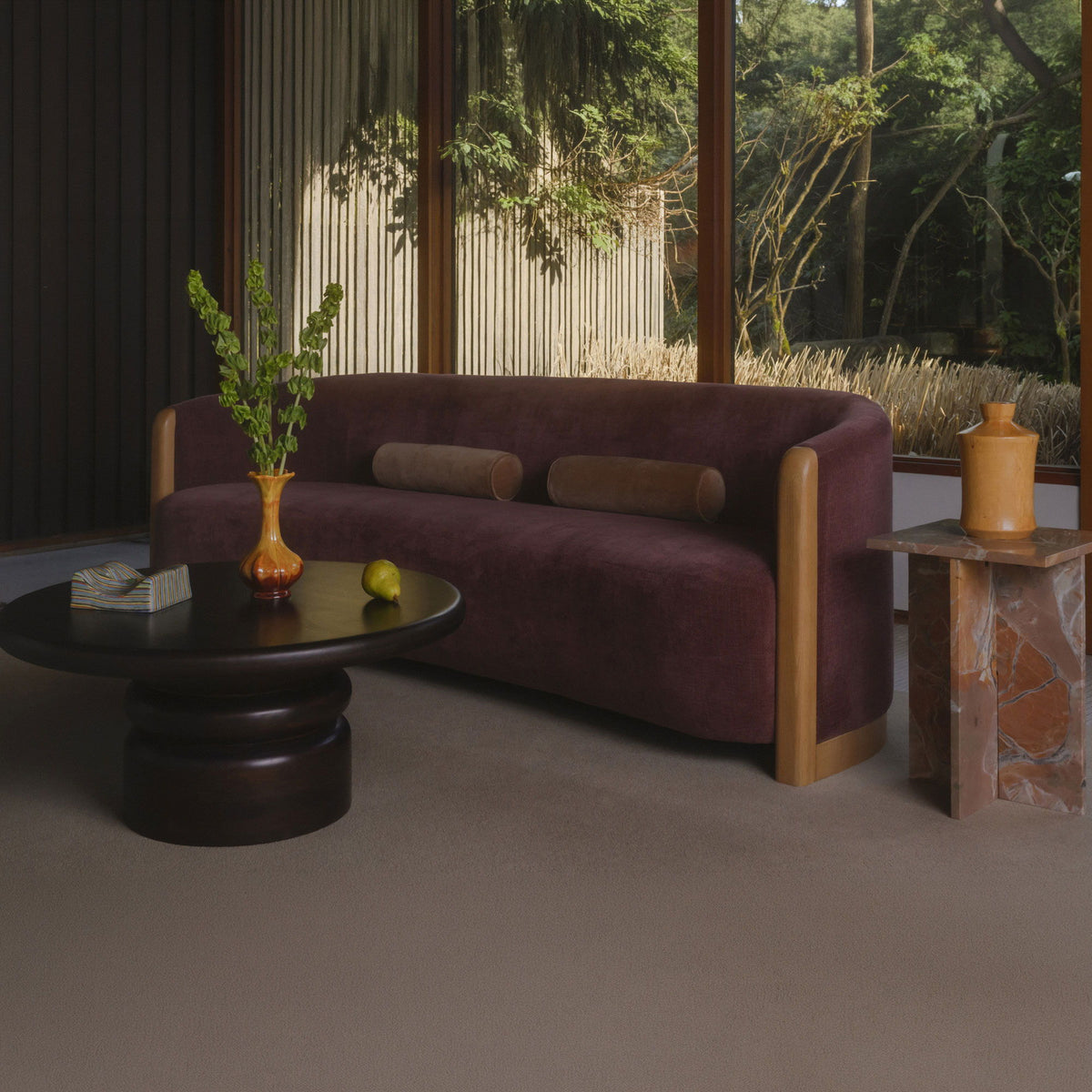 Brown round coffee table with pedestal base, plant vase on tabletop