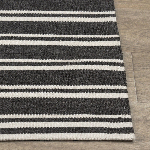 Corner view of charcoal and white striped rug with flat weave and stitched edge