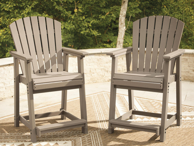 Medium brown wooden outdoor barstools with slatted backrests and armrests