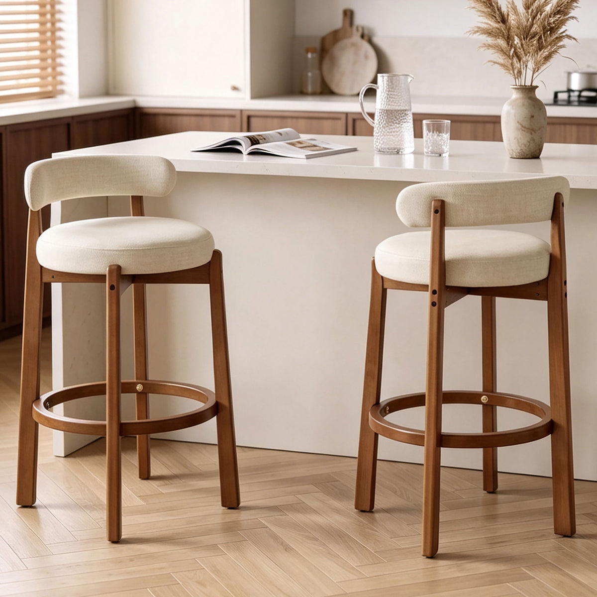Pair of beige upholstered bar stools with curved backs and walnut frames and footrests
