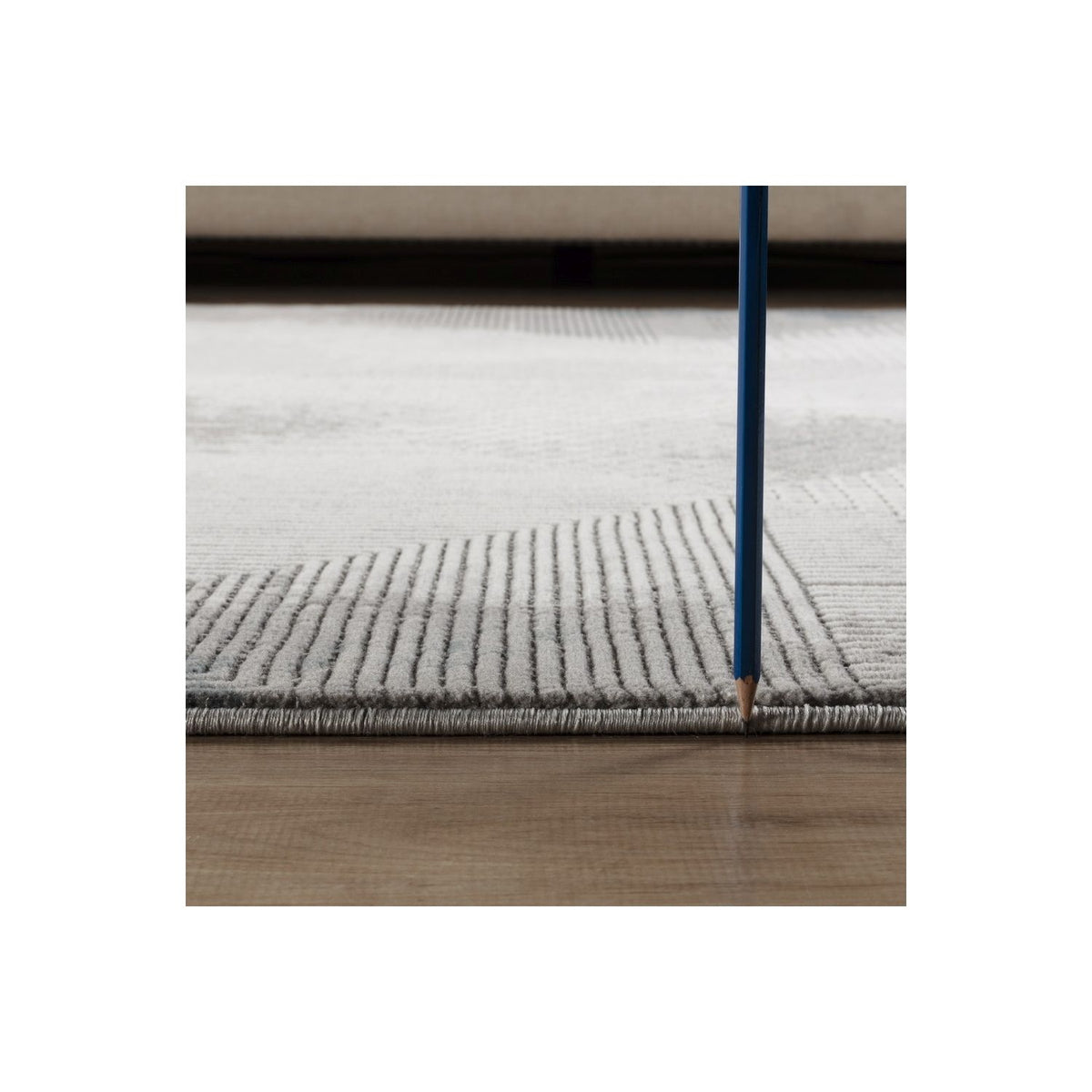 Gray geometric area rug edge with short pile texture, close-up