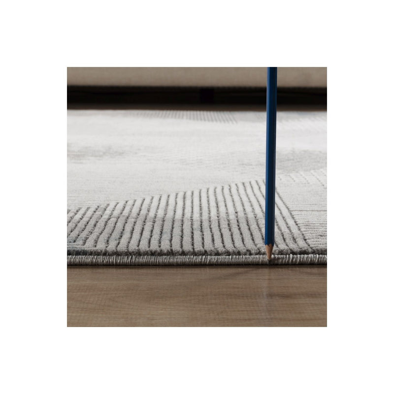 Gray geometric area rug edge with short pile texture, close-up