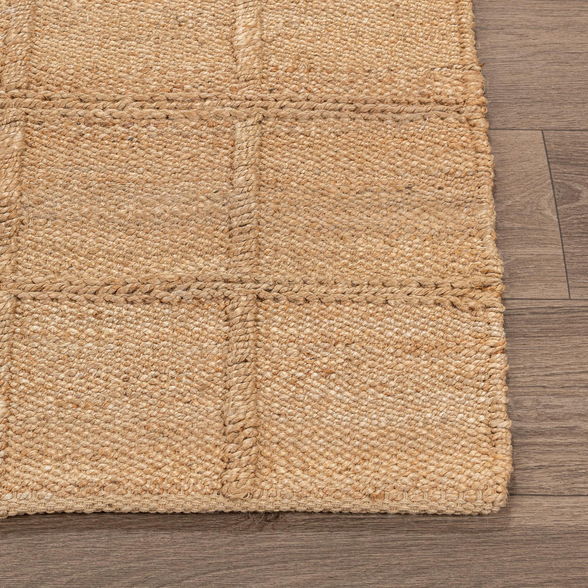 Tan jute area rug close-up with woven grid squares and stitched border edge