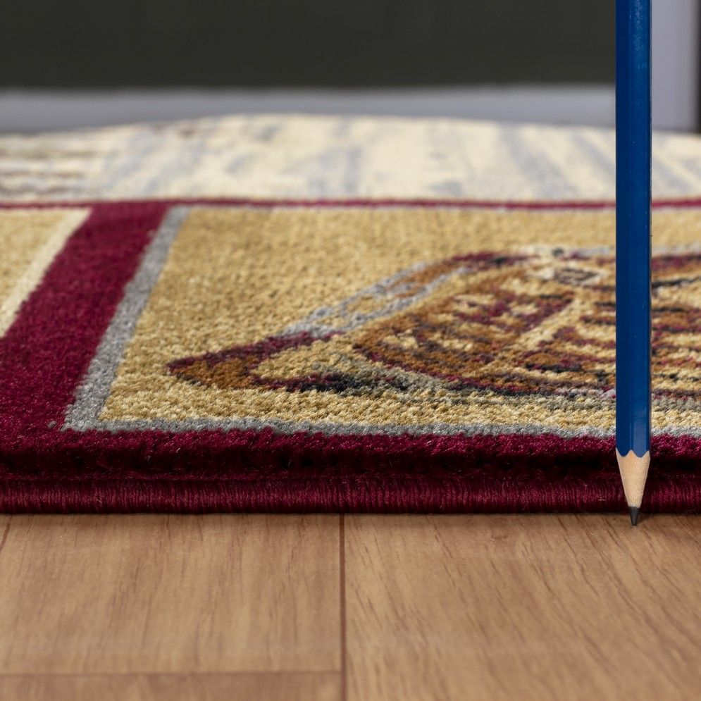 Rug edge close-up with dark red border and textured pile, cream framed vintage motifs